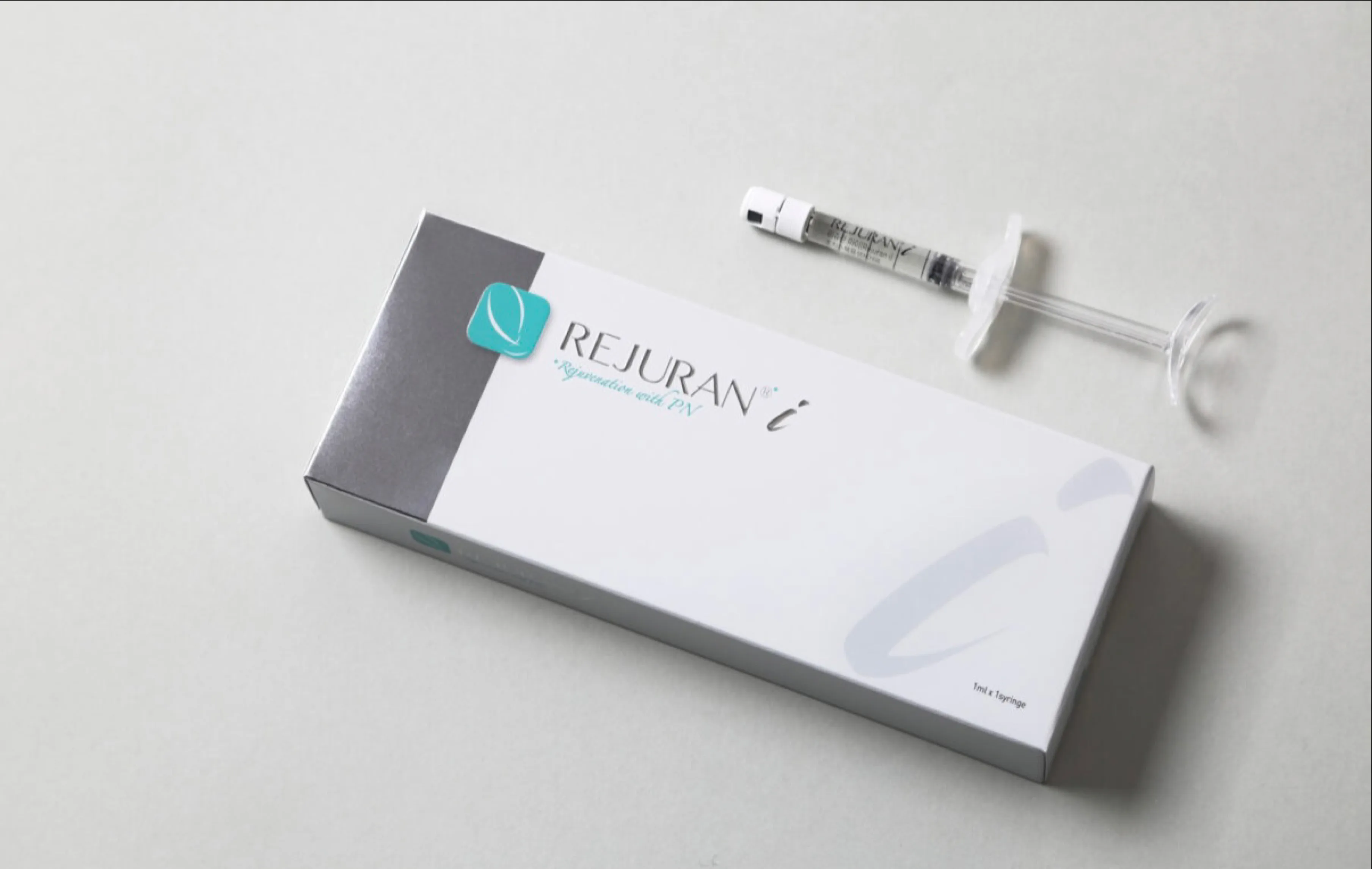 Rejuran i carton and pre-filled syringe arranged on soft grey surface
